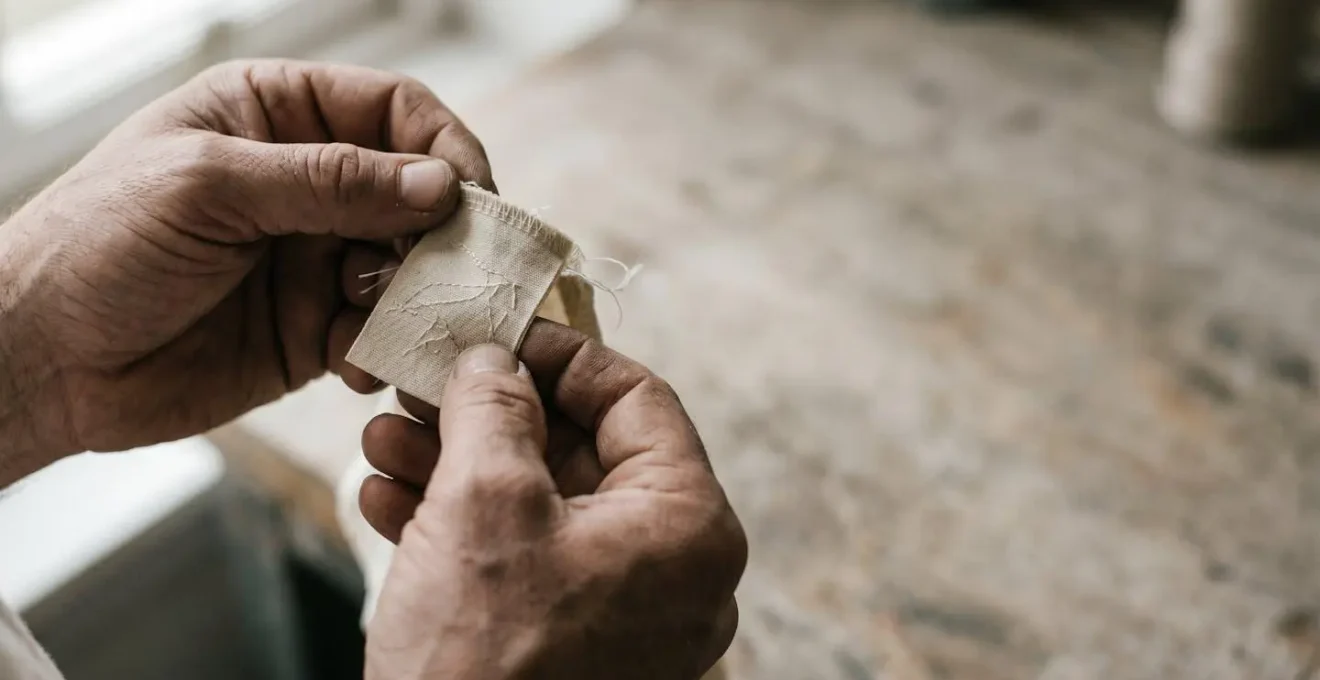 Main tenant une étiquette de vêtement textile avec fils de coton naturel et détails de confection artisanale
