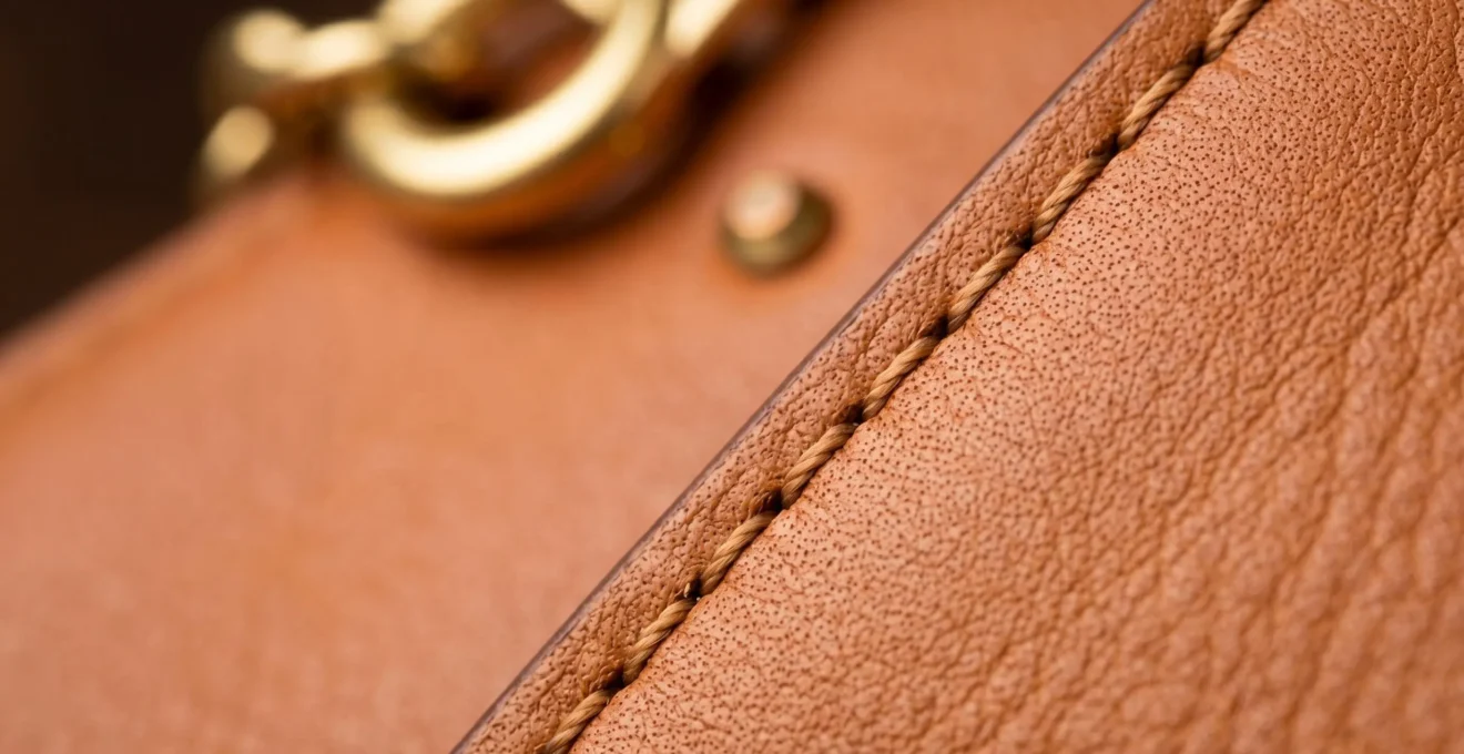 Gros plan sur les détails d'un sac de luxe vintage en cuir avec coutures et fermoir métallique, mise au point sélective